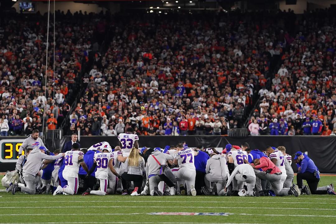 Buffalo Bills Damar Hamlin suffered a heart stoppage during a Monday Night NFL game, the Bills in the photo are kneeling and praying. Cincinnati fans were reciting the Lord's Prayer. All NFL teams texted, phoned, emailed i