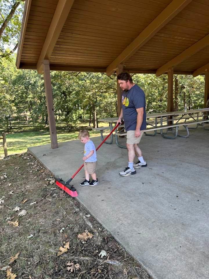 Dylan wanted to sweep the pavilion floor so his dad helped