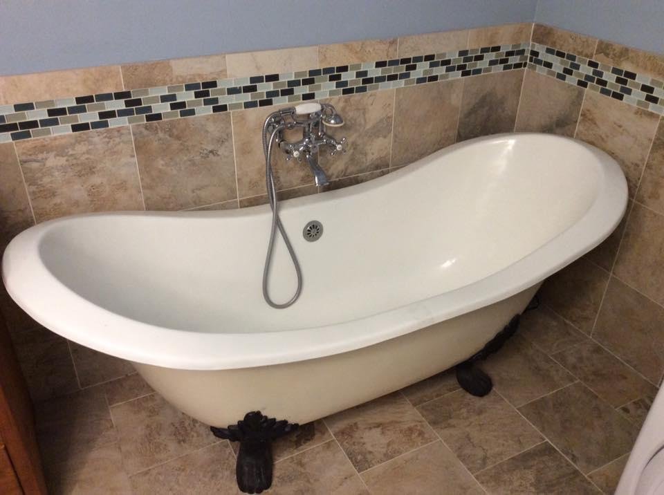 White 70” long by 30” wide white soaker tub with black claw feet