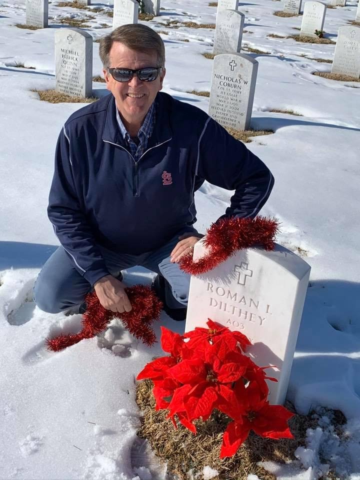 Adding a holiday ribbon to the poinsettia at the cemetery.