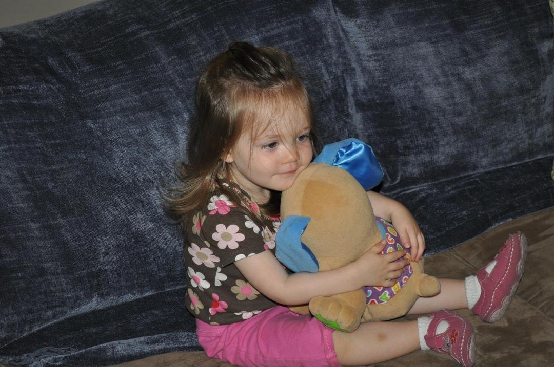 Leah in her Easter Dress and enjoying a video with her stuffed animal.