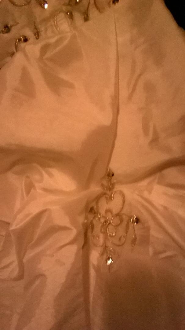 It's white in color. Custom sized roughly a size 20 and its way to long for me even in heels and I'm 5'3. Strapless wedding gown. Pictures don't do it justice asking $300 obo