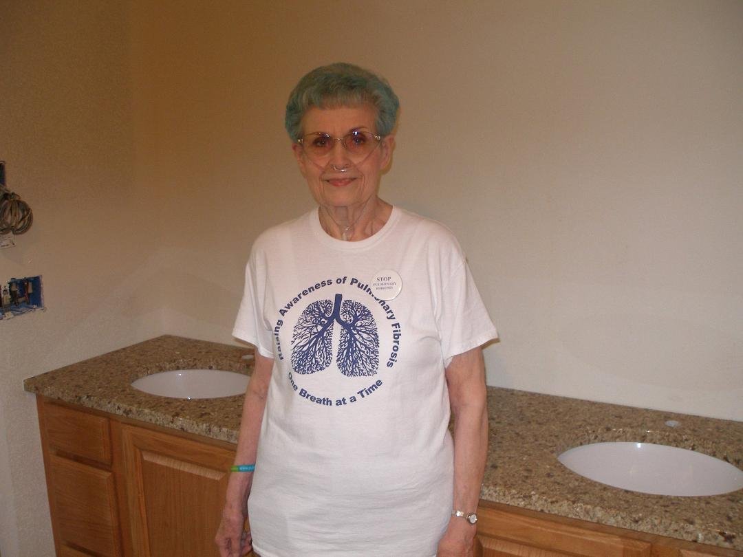 Blue haired lady standing in front of the newly installed granite countertop in the bathroom remodel project.