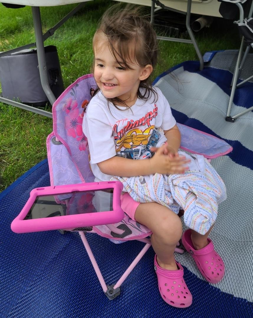My grandaughter at the Indianapolis 500. Has her Little Mermaid chair, pink I pad and shoes. Oh yes, her sleep sack.