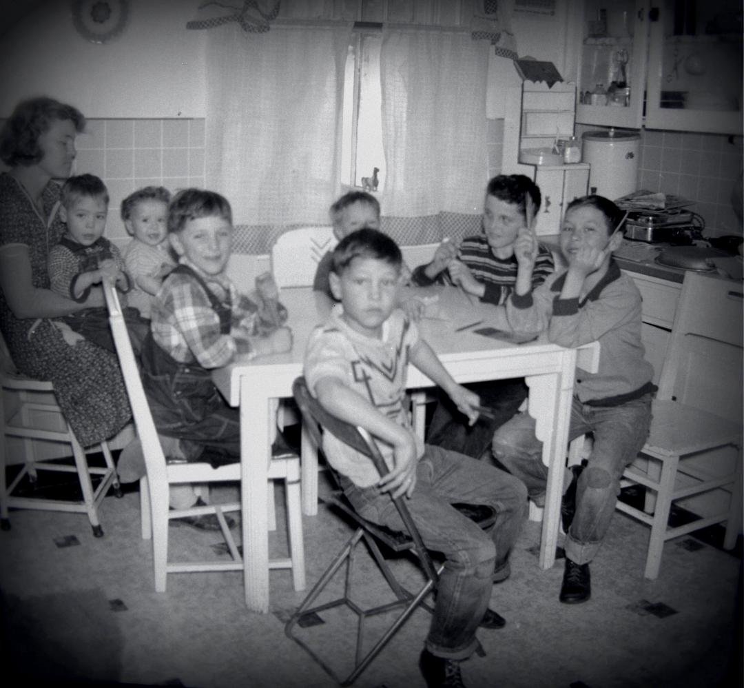 Our "McQueen Gang" in our kitchen, with Grandma Bock and Eugene. Grandma is holding Johnny and Sandy, with Johnny Shea, Eugene Bock, Danny Shea, Steve around the table. I am up front. Taken about 1952 or so.