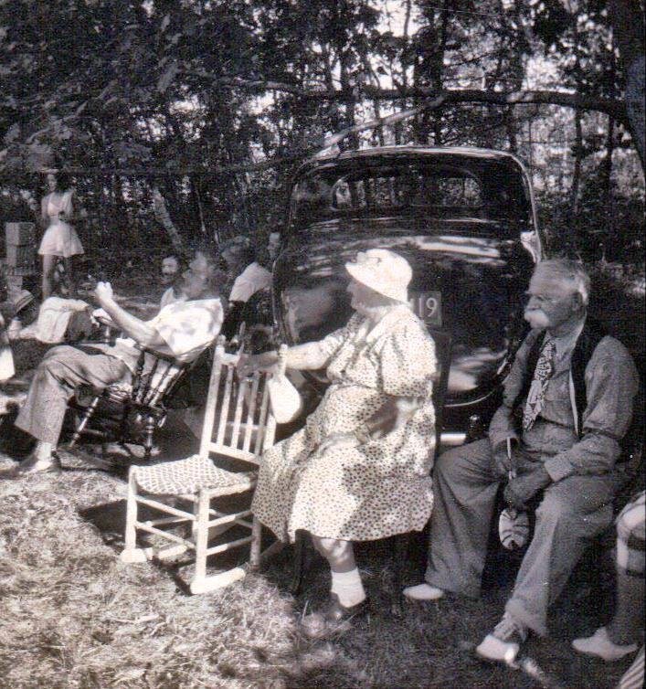 Aunt Nellie and Uncle Lew guarding their priceless antique car. Who still wears a tie and vest to a picnic?. . . and carries a very large lollipop?