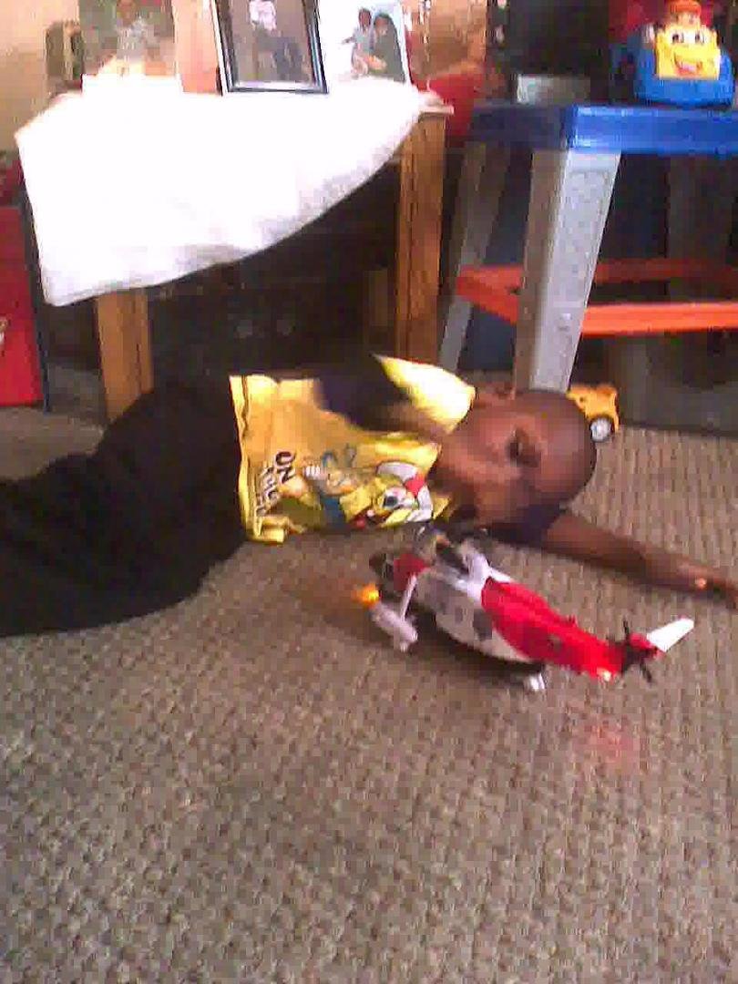HERE HE IS LAYING ON THE FLOOR PLAYING WITH HIS HELICOPTER!
