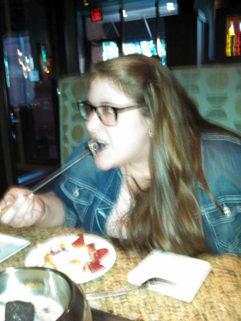 Devon eating her dessert dipped in melted white chocolate.