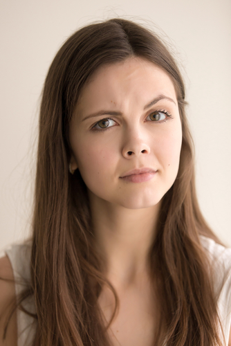 Headshot portrait of skeptic young woman. Beautiful teen girl with distrustful facial expression looking at camera with suspiciousness. Cute female feeling mistrust and doubt. Close up. Front view.