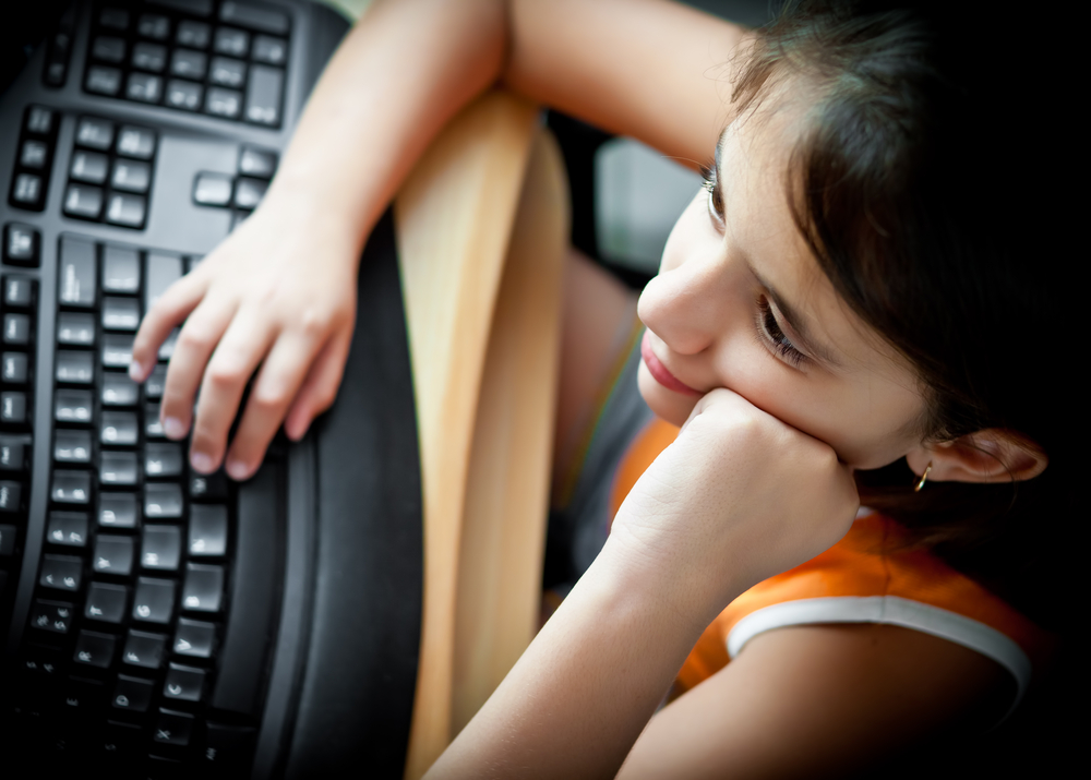 Girl working on a personal computer at home.