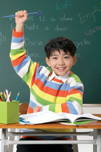 Elementary school boy raising his hand in class.