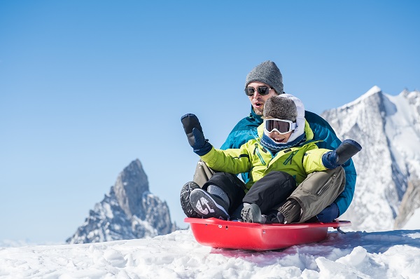 Father and son sledding during winter holiday