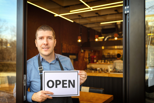 Portrait of a business owner holding open sign.