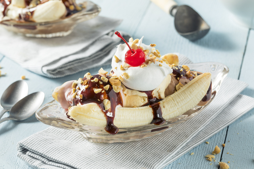 Banana split ice cream dessert with chocolate syrup, nuts, and whipped cream.