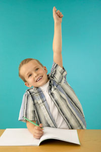 Elementary school boy raising his hand in class.