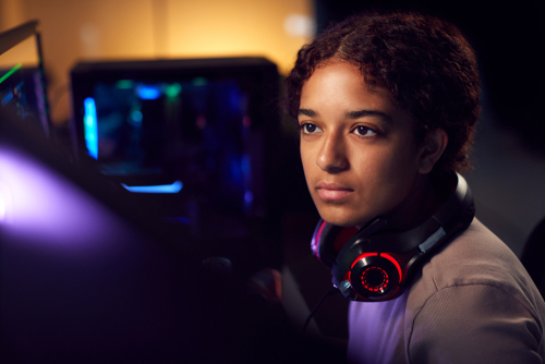 Teenage Girl With Headset Using Dual Computer Screens