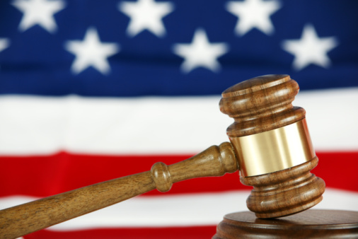 Wooden gavel with American flag behind it