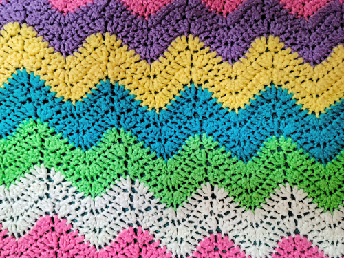 Colorful yarn in crochet zigzag pattern background.