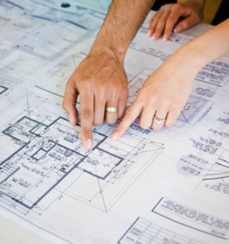 Hands pointing to an architect drawing of a building plan.