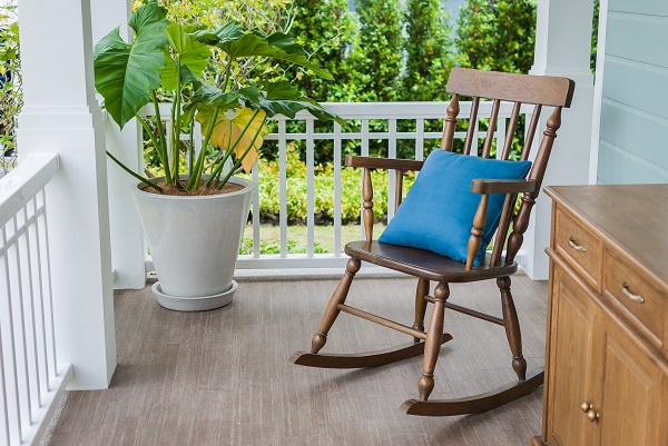 wooden rocking chair on front porch with pillow