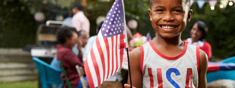 Young black boy holding flag at 4th July family garden