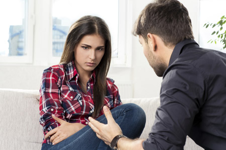 young woman, looking hurt, sitting across from a young man