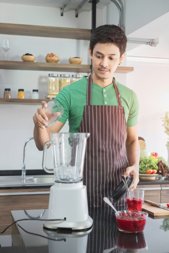 Young man making a drink with a juicer.