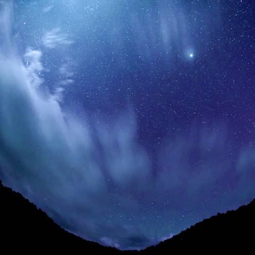 Blue night sky with stars , moving clouds and mountains