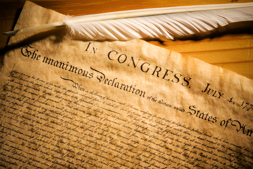 Declaration of Independence with feather quill on wood surface