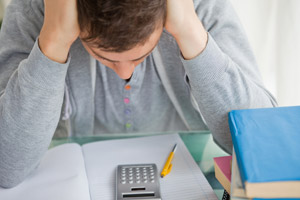 frustrated student looking down at notebook and calculator
