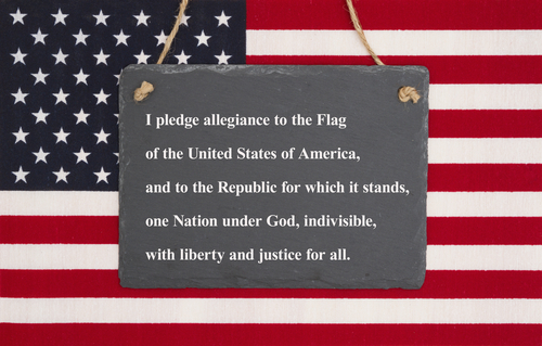 The pledge of allegiance written on a weathered chalkboard over the United States of America flag