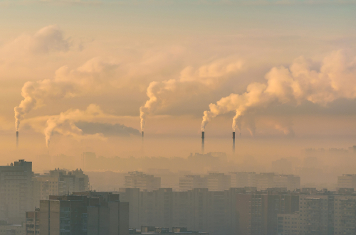 Urban landscape smoked polluted atmosphere from emissions of plants and factories, view of pipes with smoke and residential apartment buildings.