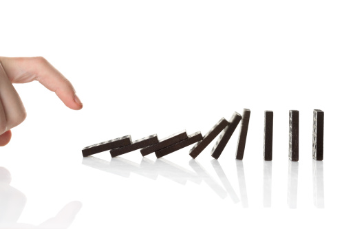 Hand pushing dominos over.