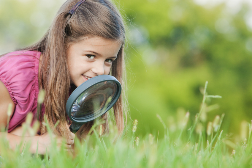 girl looking through magnifying glass