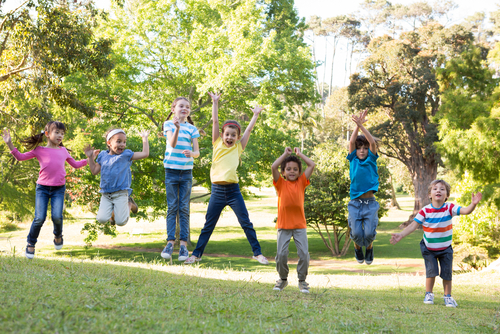 Children jumping in the park on a sunny day.