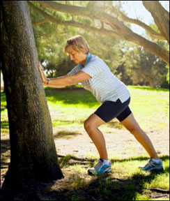 Woman stretching in a park using a tree