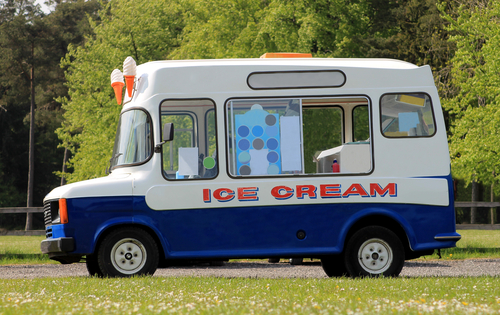 Side view of ice cream van in green countryside.