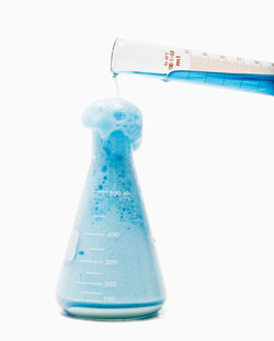blue liquid being poured into an erlenmeyer flask