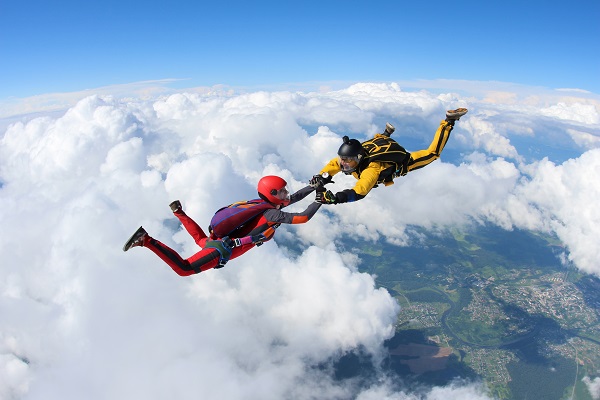 Two skydivers are falling in the background of the white clouds