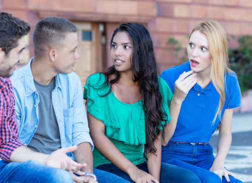 Group of young adult men and woman in discussion outside.