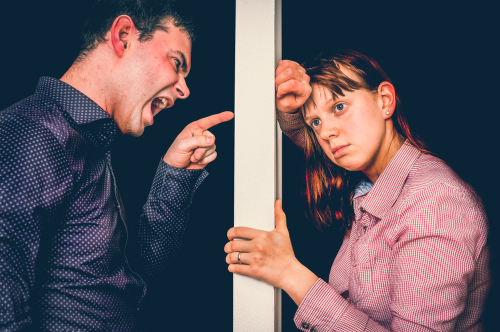 Unhappy couple arguing through a door.