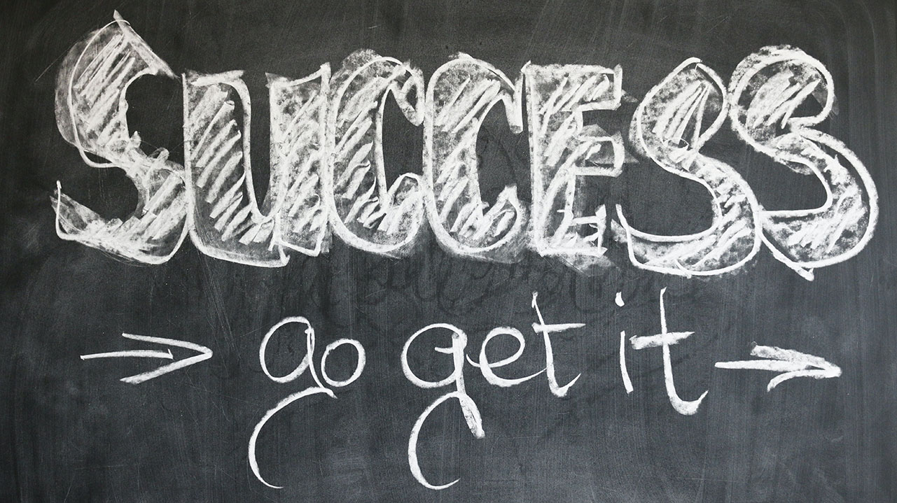 Success, right arrow, go get it, right arrow, written on a chalk board in white chalk