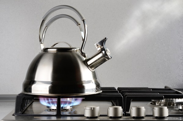 Tea kettle with boiling water on gas stove