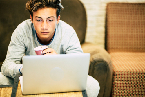 teenage boy home on the sofa with his laptop 