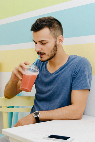 of stylish man drinking smoothie in a bar.