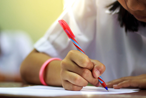 Close-up of writing hands of uniform students at course.