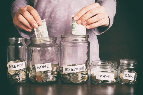 Hand's women putting coin in money jar with text.