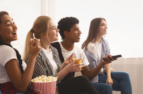 Teen friends watching tv and eating popcorn
