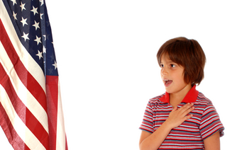 Elementary girl saying the Pledge of Allegiance toward a large American Flag. Isolated on white.