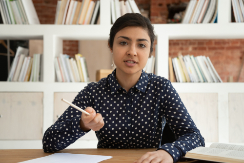 Serious young female sitting at desk with books.